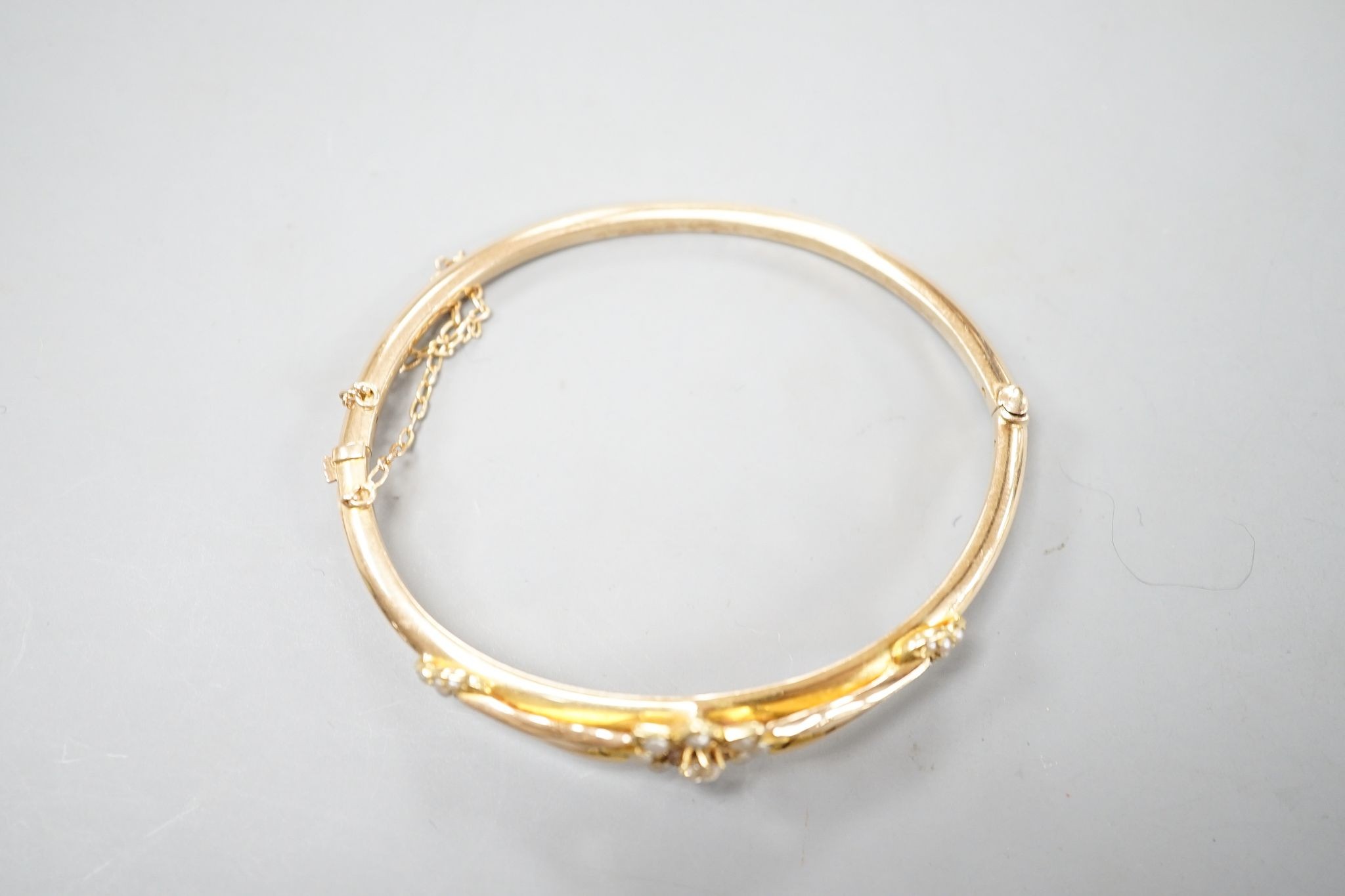 An early 20th century yellow meta diamond and seed pearl set hinged bangle, gross 9.5 grams.